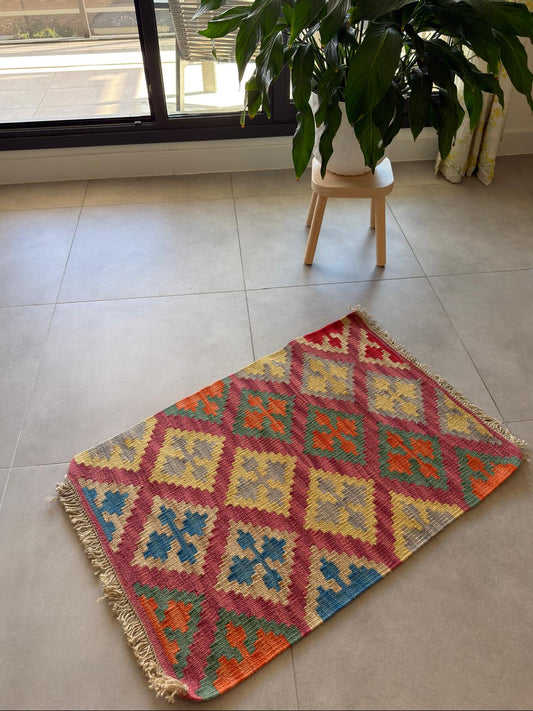 Colorful geometric-patterned rug on a tiled floor.