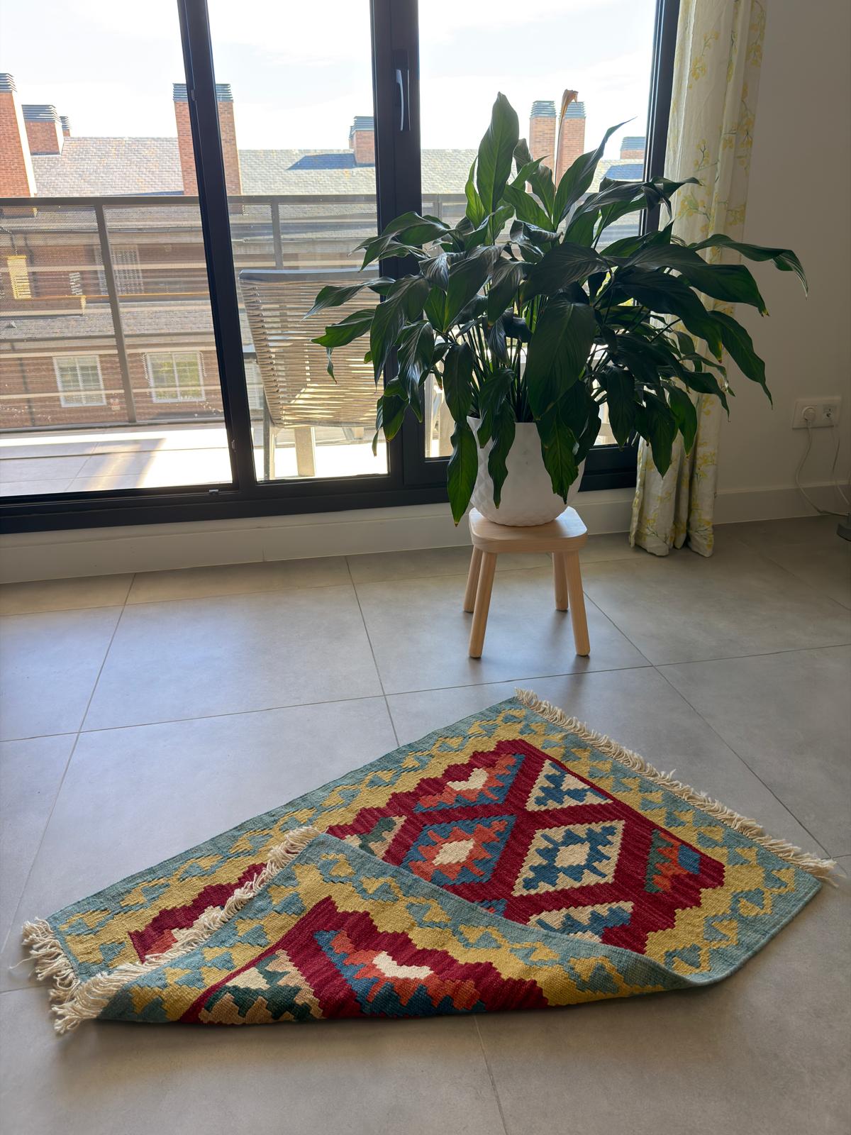 Colorful geometric-patterned rug on a tiled floor.