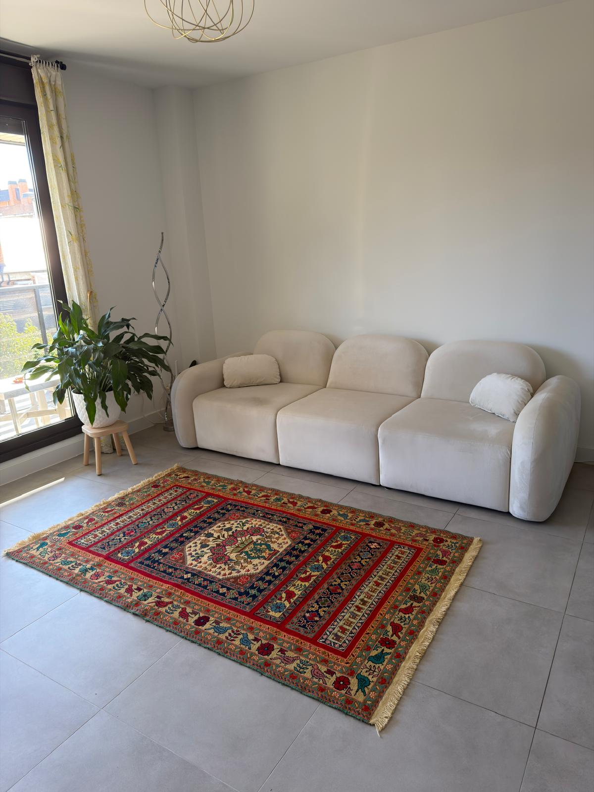 Living room with a beige sofa and a colorful patterned rug.