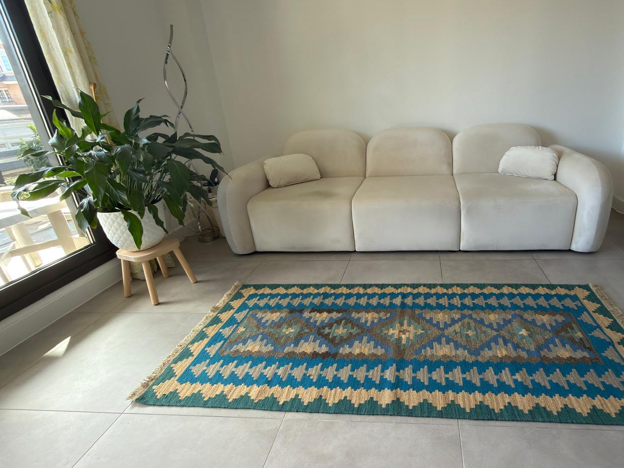 Living room with a beige sofa and a patterned rug on a tiled floor.