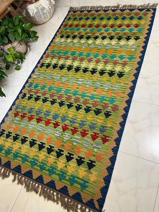 Colorful patterned rug on a tiled floor with plants in the background