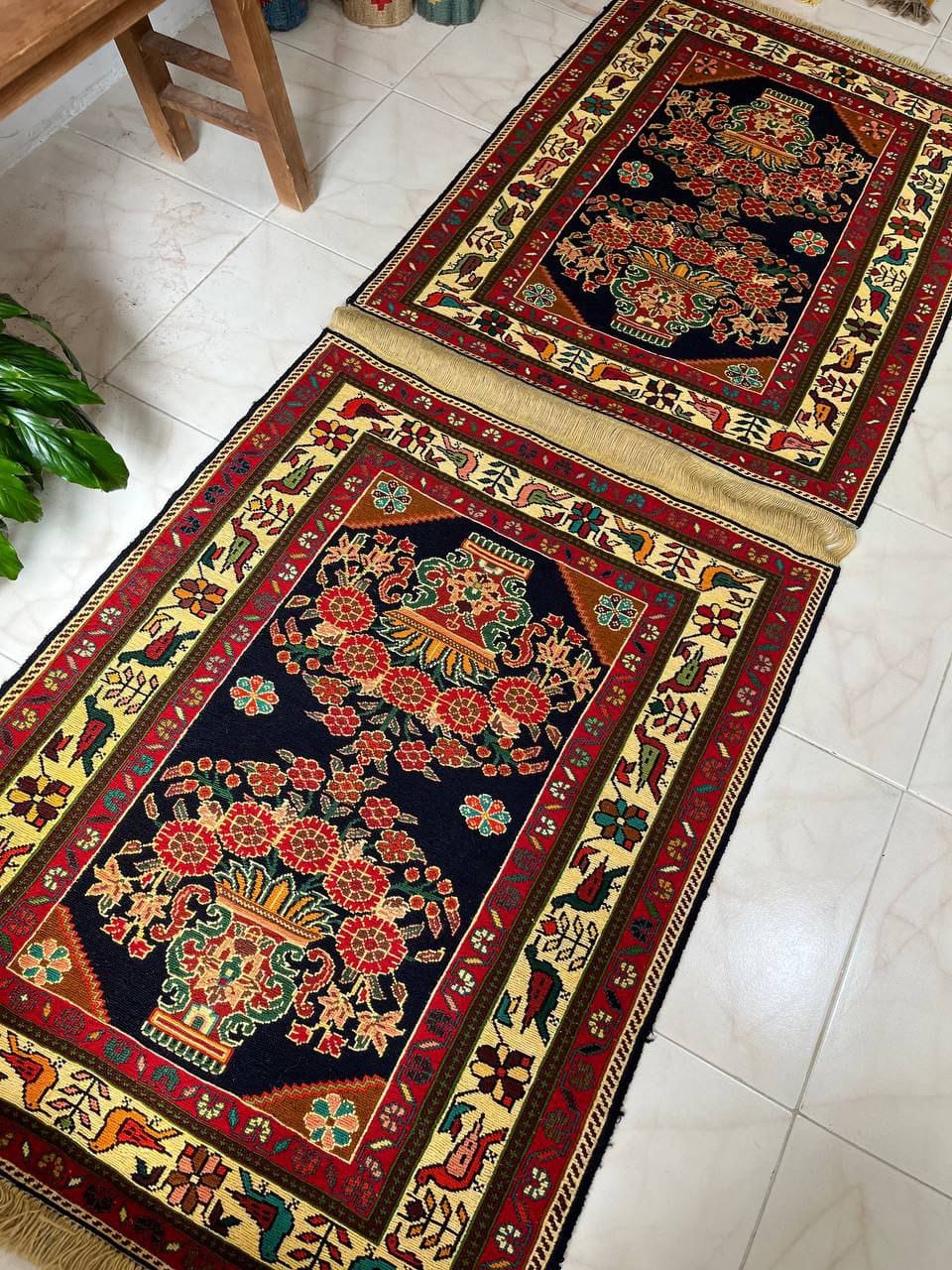 Two decorative rugs with intricate patterns on a tiled floor.