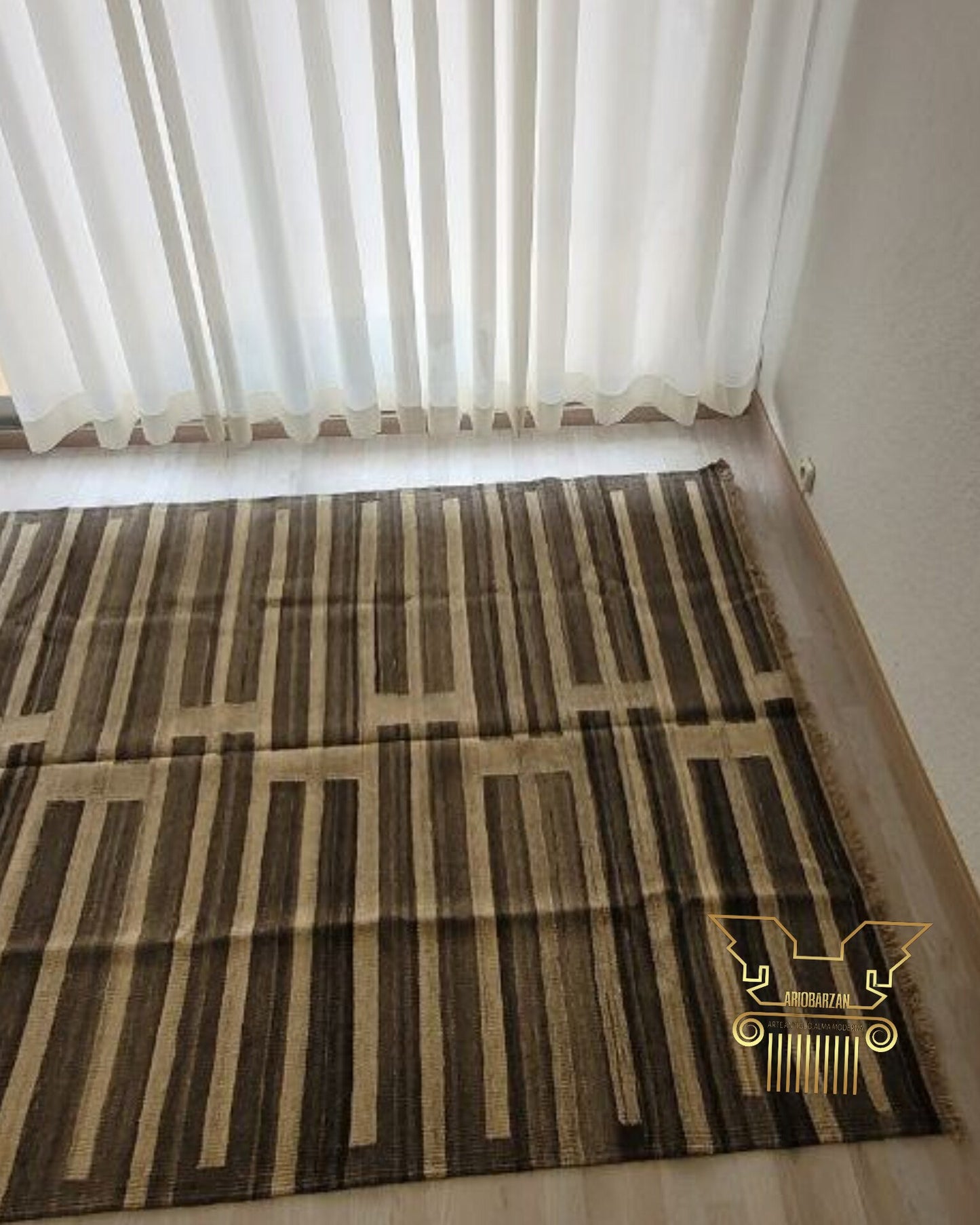 Brown patterned rug on a light-colored floor with sheer white curtains in the background.