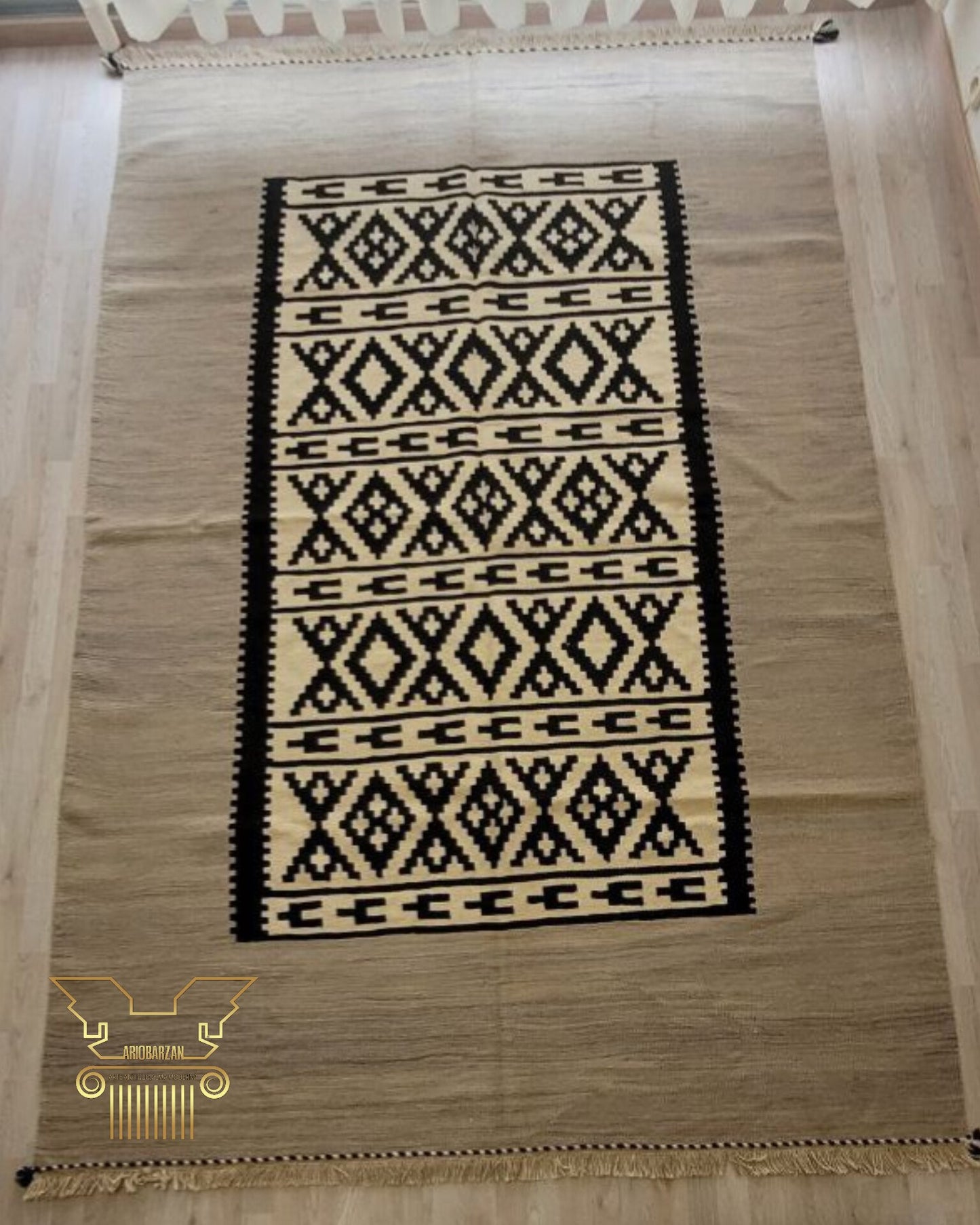 Beige rug with black geometric pattern on a wooden floor